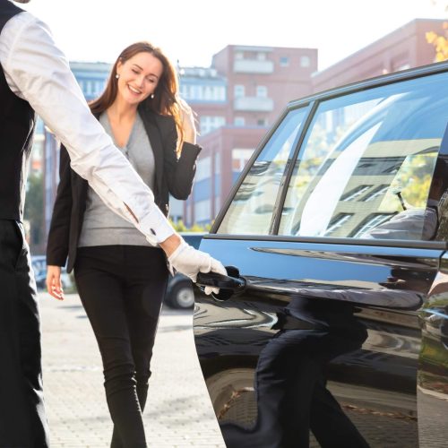 driver holding door while women coming towards car